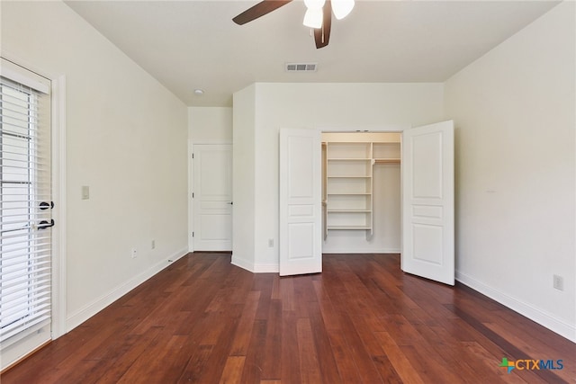 unfurnished bedroom featuring ceiling fan, a spacious closet, dark wood-type flooring, and a closet