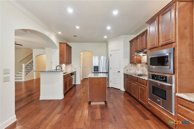 kitchen with light stone countertops, stainless steel appliances, tasteful backsplash, dark hardwood / wood-style flooring, and kitchen peninsula