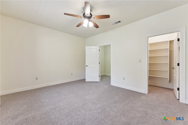 unfurnished bedroom with ceiling fan, light colored carpet, a spacious closet, and a closet