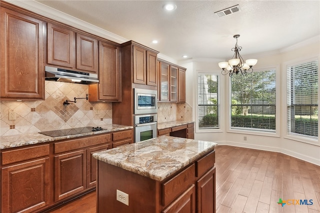 kitchen with hardwood / wood-style floors, ornamental molding, a kitchen island, stainless steel appliances, and a chandelier