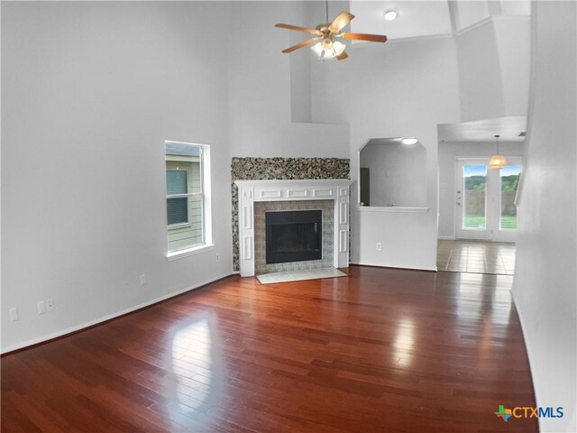 6502 Griffith Loop, Killeen, TX 76549 - unfurnished living room with a towering ceiling, wood finished floors, baseboards, ceiling fan, and a fireplace with flush hearth