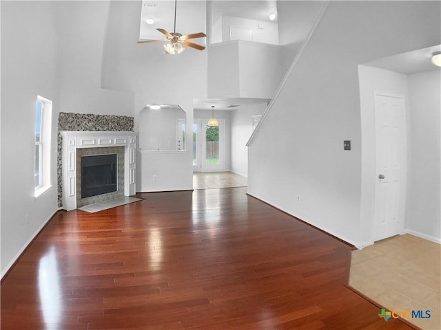 6502 Griffith Loop, Killeen, TX 76549 - unfurnished living room with a tile fireplace, a ceiling fan, baseboards, wood finished floors, and a towering ceiling