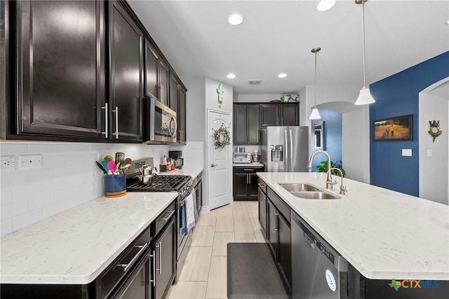 27522 Paraiso Sands, Boerne, TX 78015 - kitchen with stainless steel appliances, a kitchen island with sink, arched walkways, tasteful backsplash, and hanging light fixtures