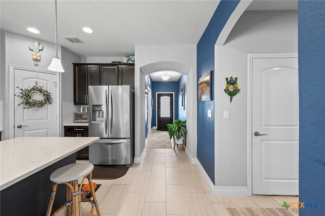 27522 Paraiso Sands, Boerne, TX 78015 - kitchen featuring stainless steel refrigerator with ice dispenser, arched walkways, decorative light fixtures, a kitchen bar, and a textured ceiling