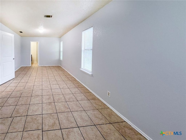 unfurnished room with light tile patterned floors and baseboards