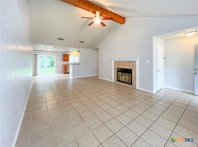unfurnished living room featuring light tile patterned floors, beam ceiling, ceiling fan, a tile fireplace, and baseboards