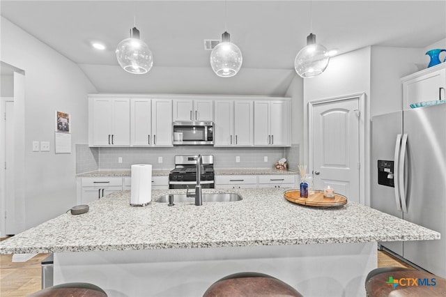 kitchen with a kitchen island with sink, appliances with stainless steel finishes, and decorative light fixtures