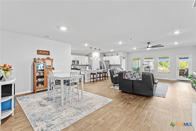 living room with light hardwood / wood-style floors, ceiling fan, and sink