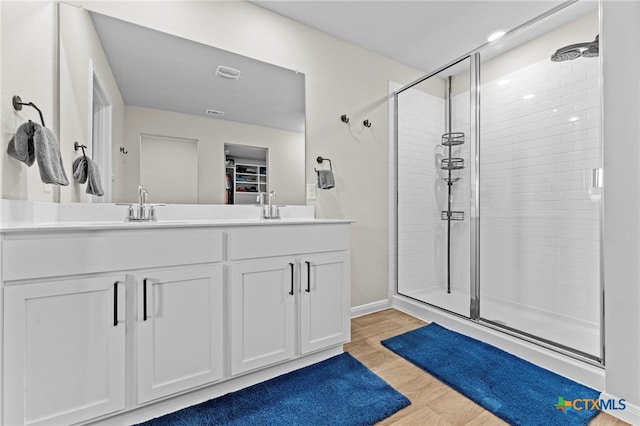 bathroom featuring walk in shower, vanity, and wood-type flooring