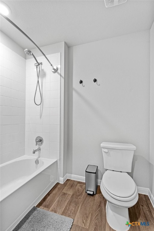 bathroom with toilet, tiled shower / bath combo, and hardwood / wood-style floors