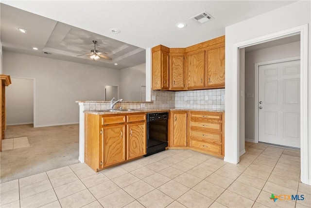 kitchen with sink, ceiling fan, black dishwasher, tasteful backsplash, and a tray ceiling