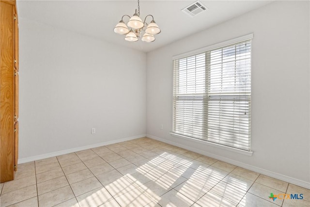 spare room with a notable chandelier and light tile patterned floors