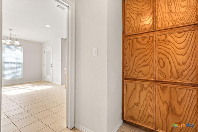 hallway featuring light tile patterned flooring and a notable chandelier