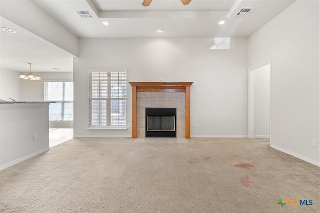 unfurnished living room with a tile fireplace, light carpet, ceiling fan, and a tray ceiling