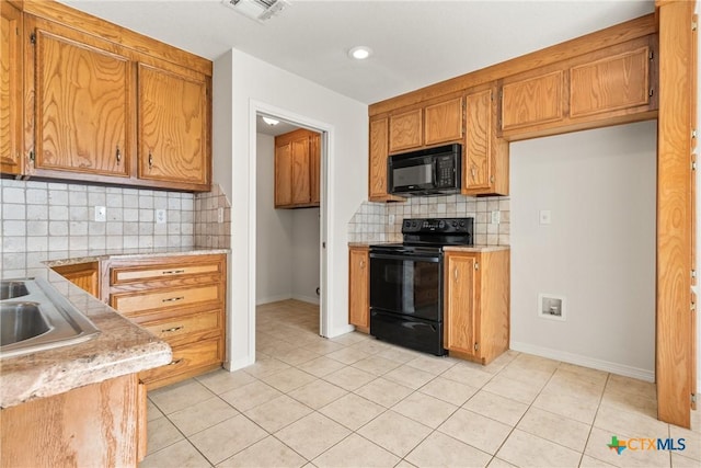 kitchen featuring tasteful backsplash, sink, light tile patterned floors, and black appliances