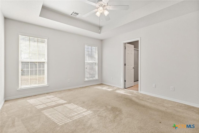 unfurnished room featuring light carpet, a raised ceiling, and ceiling fan