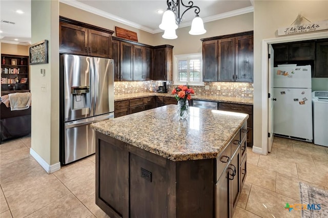 135 Wellspring Blvd, Victoria, TX 77904 - kitchen featuring appliances with stainless steel finishes, dark brown cabinets, light stone counters, crown molding, and backsplash