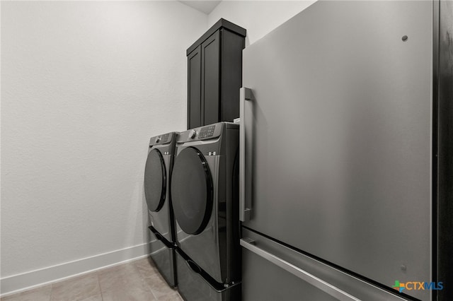 washroom featuring light tile patterned floors, cabinet space, baseboards, and washing machine and clothes dryer