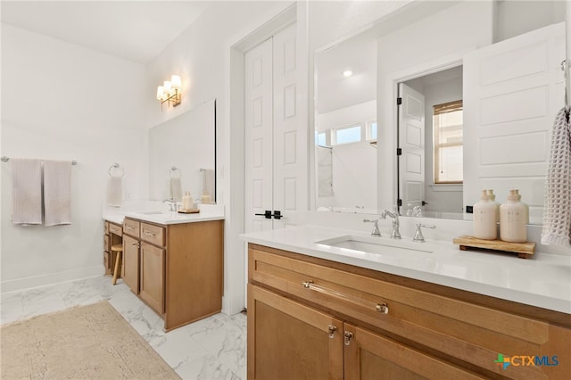 bathroom featuring a sink, baseboards, two vanities, and marble finish floor