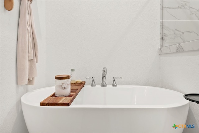 full bath featuring a sink, a soaking tub, and a textured wall