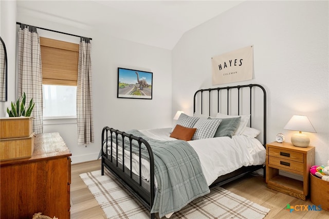 bedroom with baseboards, lofted ceiling, and light wood-style floors