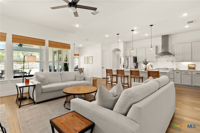 living room featuring plenty of natural light, visible vents, and light wood-type flooring