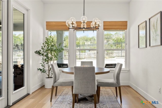 dining space with light wood finished floors, baseboards, and an inviting chandelier