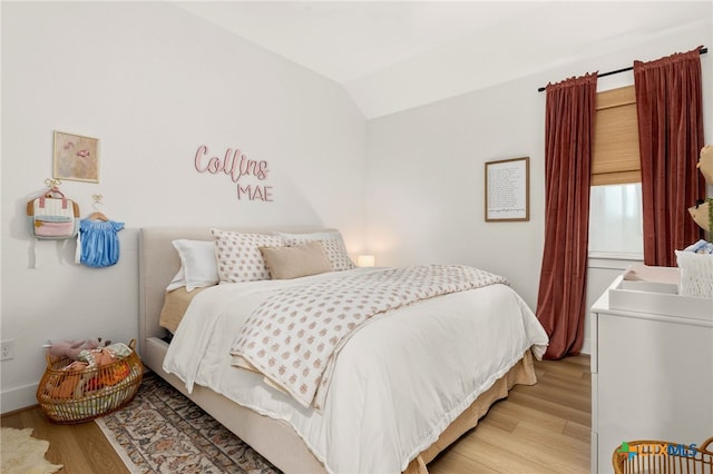 bedroom with lofted ceiling and light wood-style floors