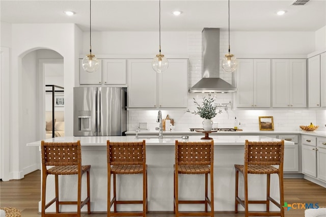 kitchen featuring dark wood finished floors, decorative backsplash, wall chimney exhaust hood, and stainless steel appliances