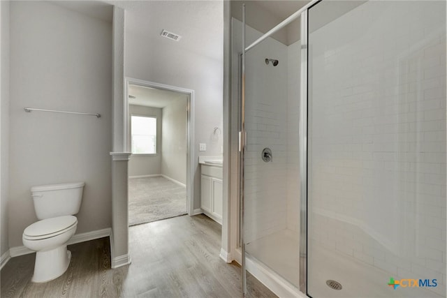 bathroom featuring hardwood / wood-style floors, walk in shower, vanity, and toilet