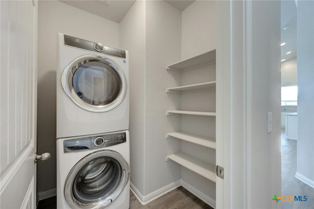 laundry room featuring stacked washer / dryer and dark hardwood / wood-style flooring