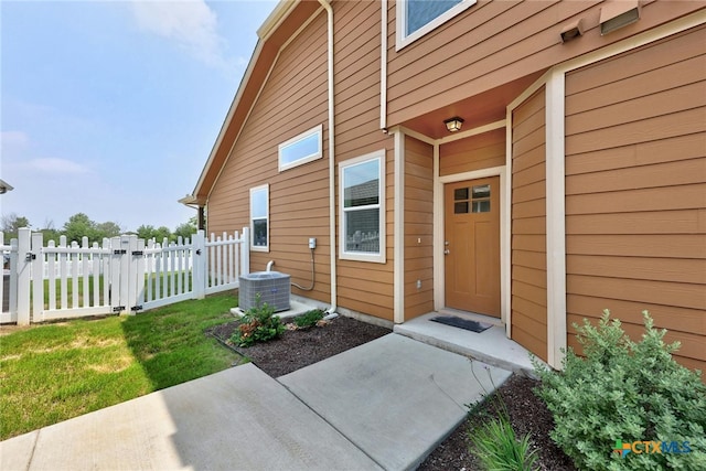 entrance to property with a lawn and cooling unit