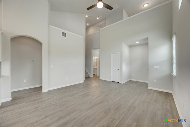 spare room with a high ceiling, ceiling fan, and light hardwood / wood-style flooring