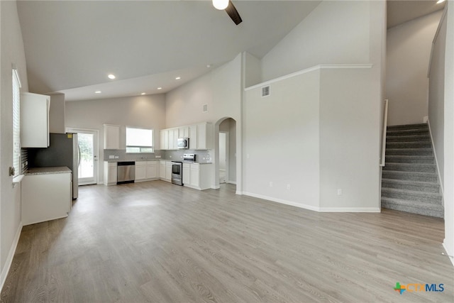 unfurnished living room with high vaulted ceiling, light hardwood / wood-style flooring, and ceiling fan