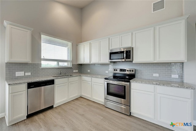 kitchen featuring light hardwood / wood-style flooring, appliances with stainless steel finishes, and white cabinets