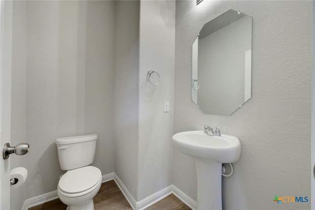 bathroom featuring toilet, sink, and hardwood / wood-style flooring