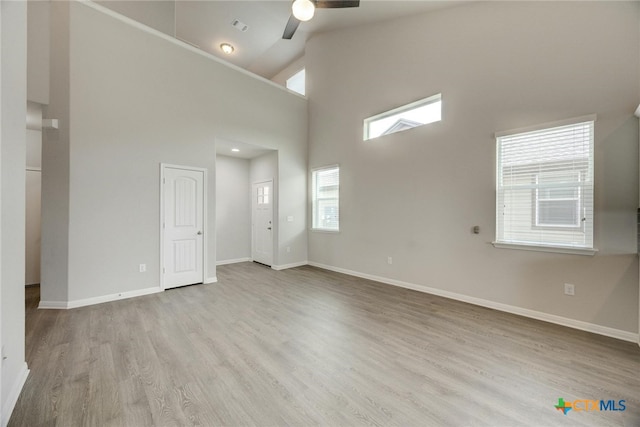 spare room with high vaulted ceiling, light hardwood / wood-style floors, and ceiling fan