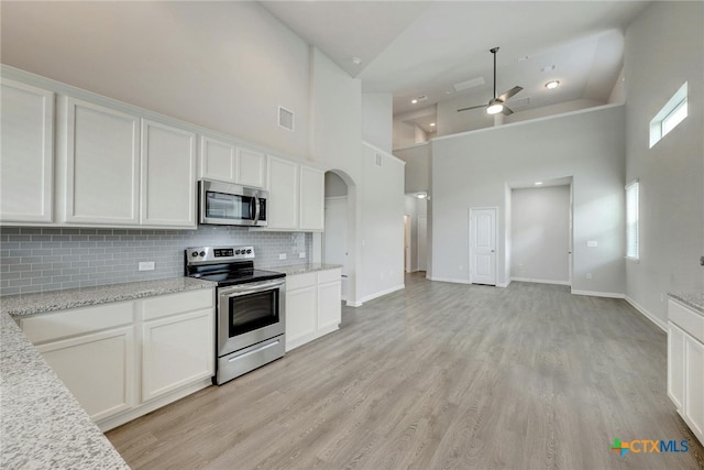 kitchen featuring a wealth of natural light, high vaulted ceiling, white cabinetry, and appliances with stainless steel finishes