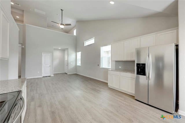 kitchen featuring stainless steel appliances, high vaulted ceiling, light hardwood / wood-style floors, white cabinets, and ceiling fan