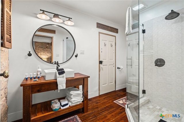 bathroom featuring hardwood / wood-style floors, sink, a shower with door, and crown molding