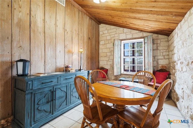 dining room with wood walls, light tile patterned flooring, wooden ceiling, and vaulted ceiling