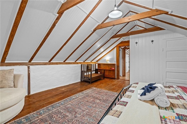 bedroom with wooden walls, lofted ceiling with beams, and hardwood / wood-style flooring