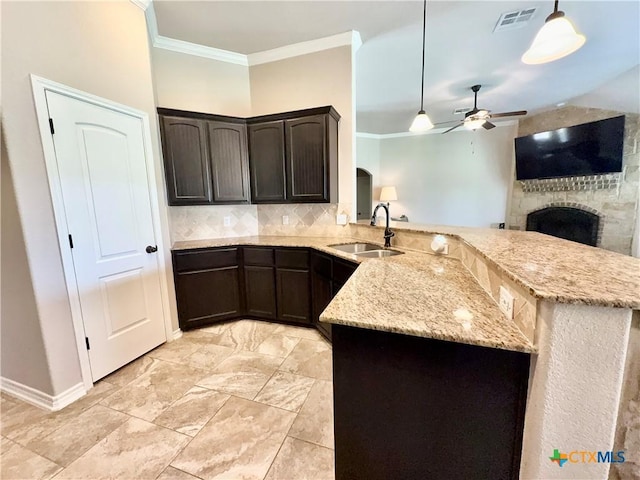 416 Coventry Dr, Temple, TX 76502 - kitchen featuring a sink, dark brown cabinets, a peninsula, a fireplace, and crown molding