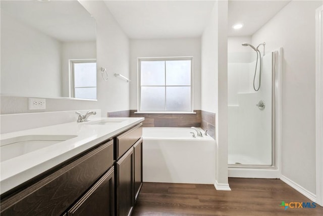 full bath with double vanity, a stall shower, a sink, and wood finished floors