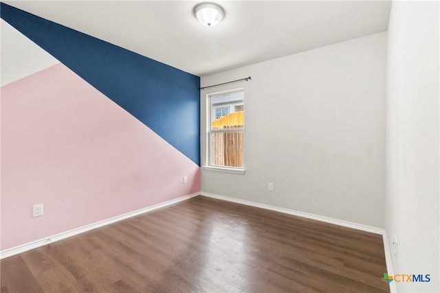 unfurnished room featuring baseboards and wood finished floors