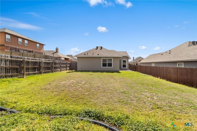 back of house with a fenced backyard and a lawn