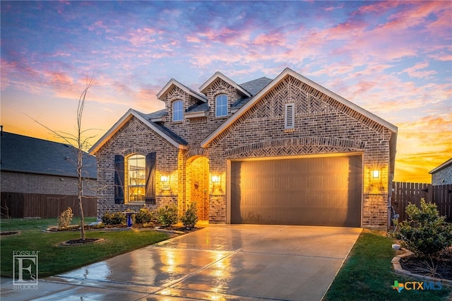 french country inspired facade with brick siding, a yard, fence, a garage, and driveway