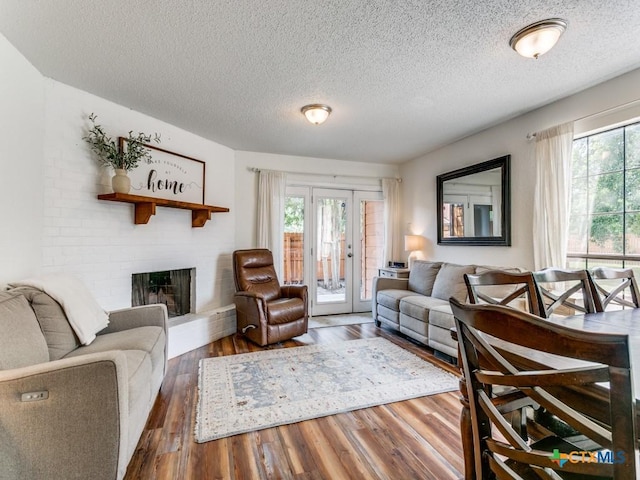 1133 Ashby St, Seguin, TX 78155 - living area featuring a textured ceiling, healthy amount of natural light, a brick fireplace, and wood finished floors