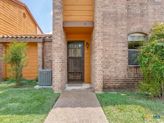 property entrance with central AC unit and a lawn