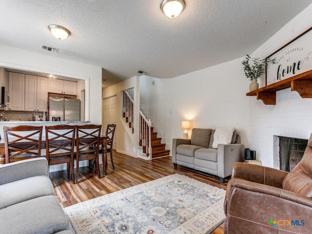 1133 Ashby St, Seguin, TX 78155 - living area with light wood finished floors, stairs, a textured ceiling, a fireplace, and baseboards